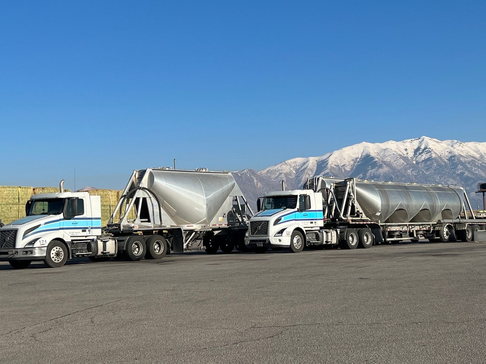 Two Handy Truck Line trucks with dry bulk trailers in front of Utah mountains